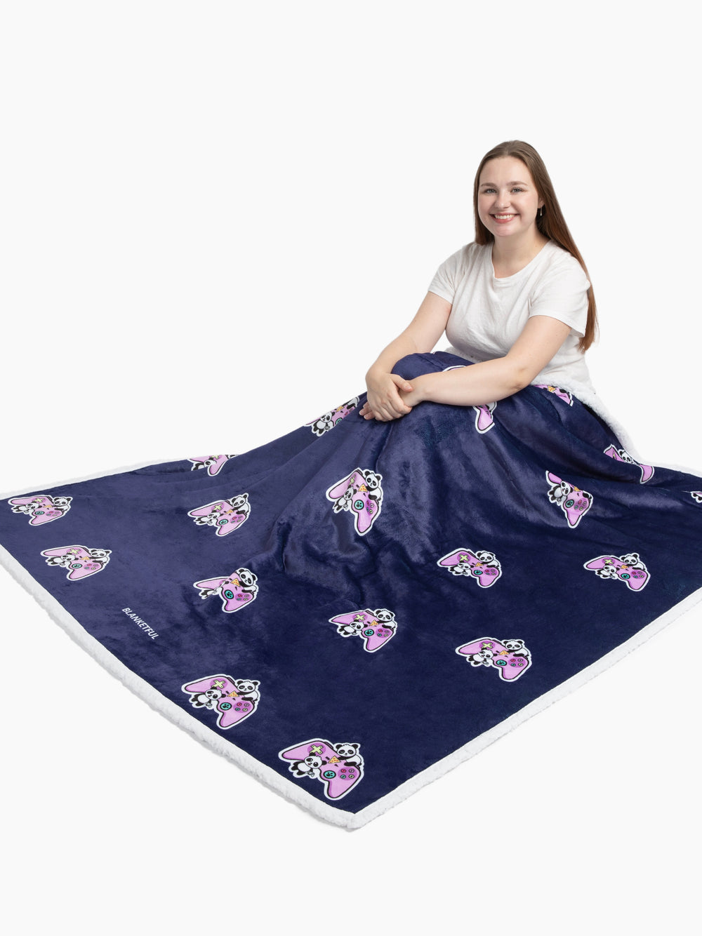 Person sitting on a large navy blanket with pink and white designs on a white background